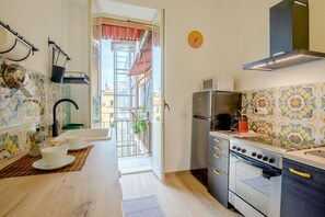 A kitchen with a stove, microwave, and sink. - Candia Cento Apartment Vatican Museums (Rome)