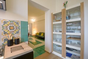 A kitchen with a tiled backsplash, a countertop with utensils, and a cabinet with glass doors. - Candia Cento Apartment Vatican Museums (Rome)