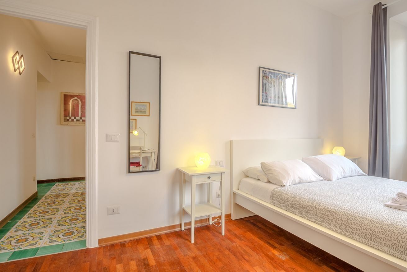Een slaapkamer met een bed, nachtkastje en spiegel.