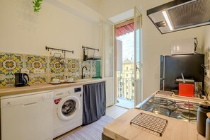 A compact kitchen with a washing machine, a stove, and a view of the city. - Candia Cento Apartment Vatican Museums (Rome)