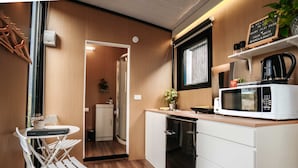A compact kitchen with a microwave, a small refrigerator, and a white cabinet. - Kiwi Farm Cabin 2 by Tiny Away (Waitoki)