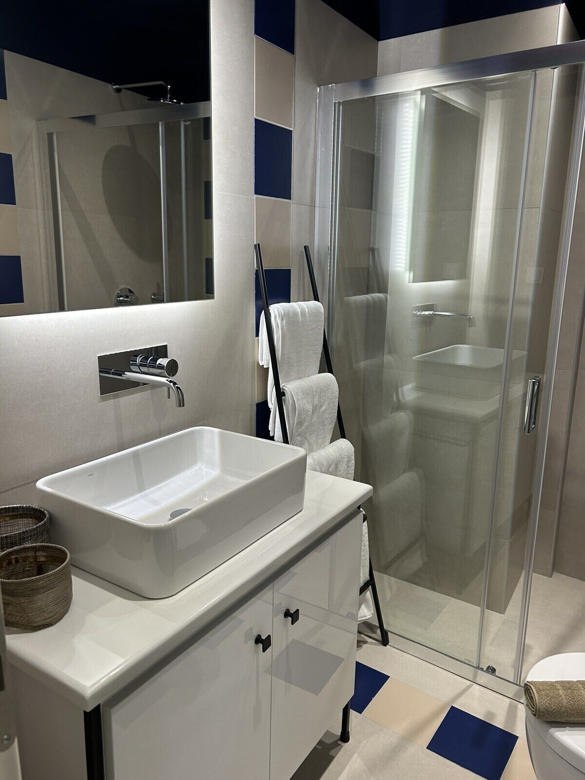 A modern bathroom with a white sink, a glass shower enclosure, and a large mirror.