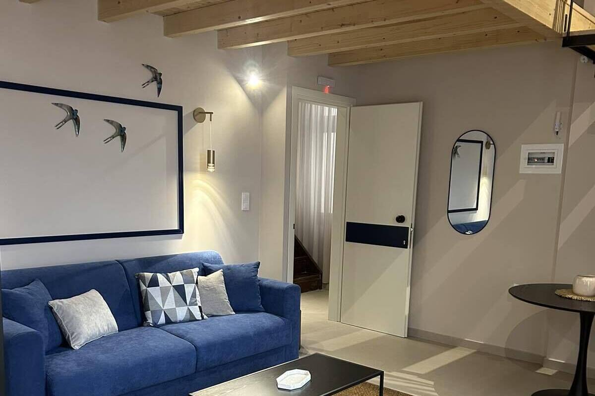 A modern living room with a blue sofa, a coffee table, and a large mirror.