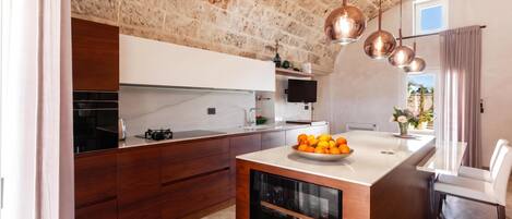 A modern kitchen with a stone wall, wooden cabinets, a built-in wine rack, and a dining area with a table and chairs.