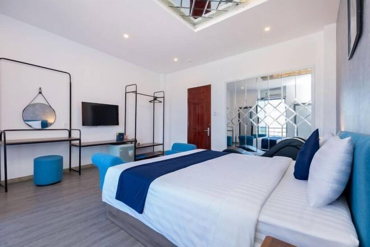 Habitación de hotel moderna con una cama grande, un escritorio, una silla, un televisor y una ventana con vistas.