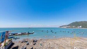 A rocky beach with boats and a clear blue sky. - Joi Home Beachfront (Ho Chi Minh City)