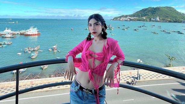 A person standing on a balcony overlooking a coastal area with boats and a distant hill. - Joi Home Beachfront (Ho Chi Minh City)