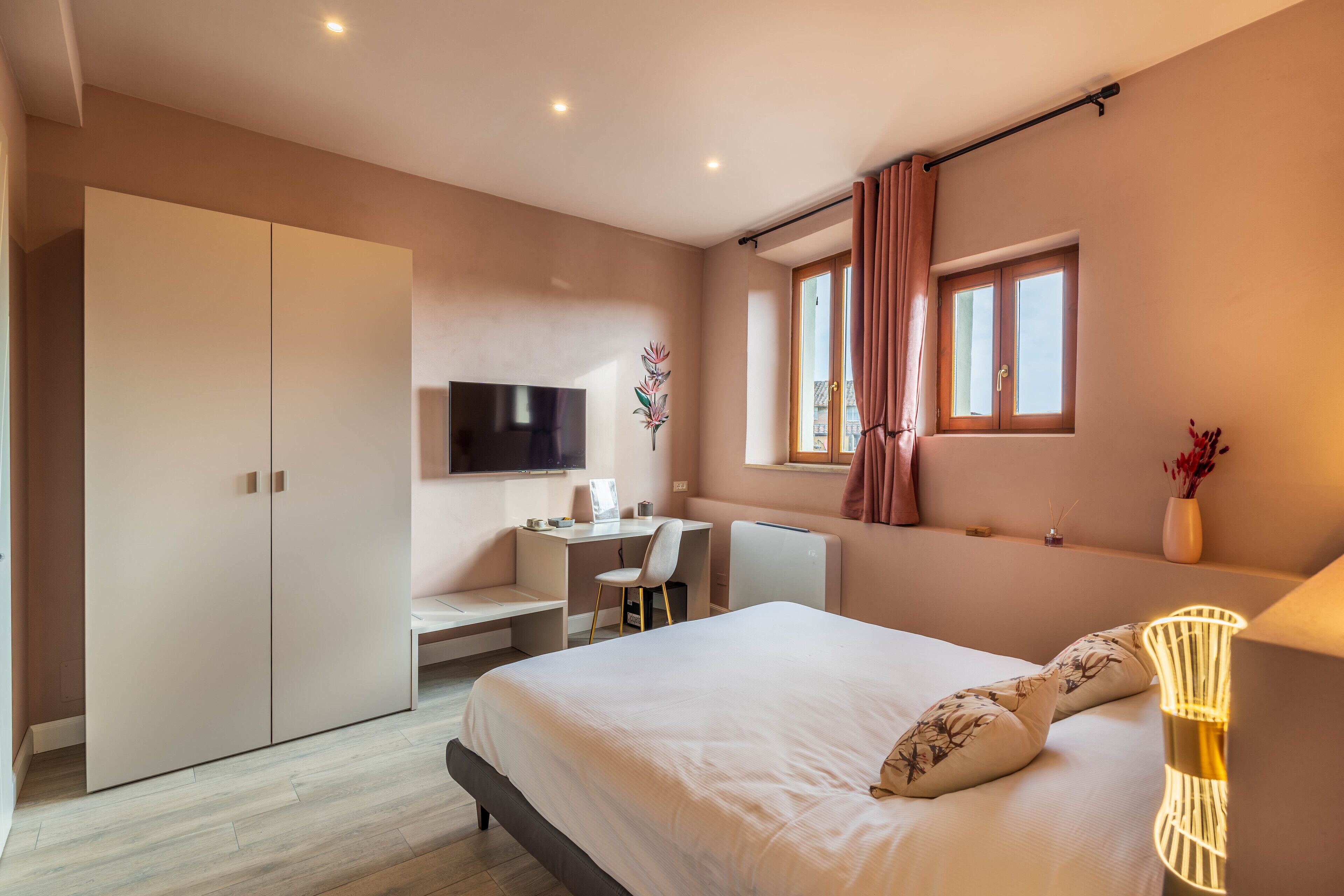 A bedroom with a bed, a desk, a TV, and a wardrobe.
