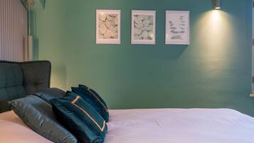 Een slaapkamer met een bed, kussens en drie ingelijste kunstwerken aan de muur.