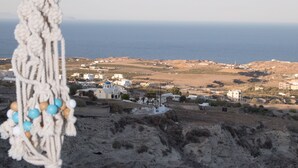 A macrame decoration hanging in a room with a view of a coastal landscape. - Eunoia apartments (Santorini)