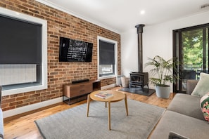 Una sala de estar con pared de ladrillo, chimenea, televisor y sofá.