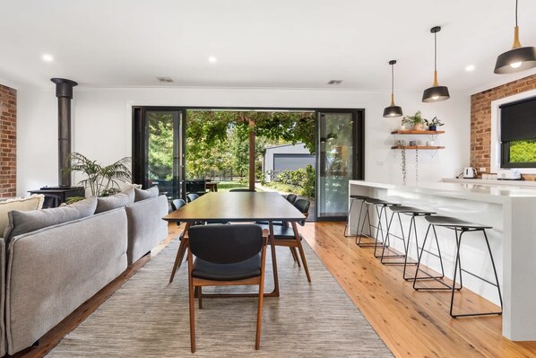 A modern kitchen with a central island, bar stools, and a dining area with a table and chairs.