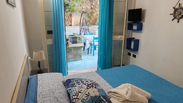 Un dormitorio con una cama, televisión y vistas a un patio exterior.