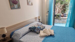Una cama bien tendida con una colcha estampada y almohadas, una lámpara de noche y un cuadro en la pared.