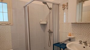 Un baño con ducha, inodoro, lavamanos y ventana.