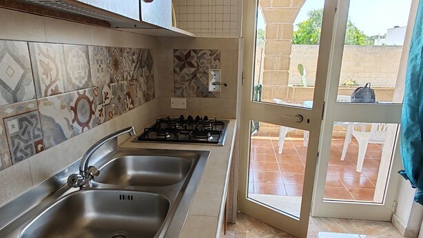 A kitchen with two sinks, a gas stove, and patterned tiles. - Apartment with Veranda 200 meters from the waterfront (TORRE SAN GIOVANNI)