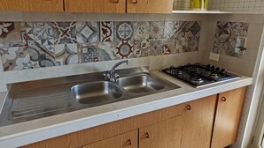 A kitchen with a double sink, stainless steel faucet, and a gas stove. - Apartment with Veranda 200 meters from the waterfront (TORRE SAN GIOVANNI)