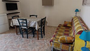 A compact living space with a dining table, chairs, a sofa, a TV, and a lamp. - Apartment with Veranda 200 meters from the waterfront (TORRE SAN GIOVANNI)