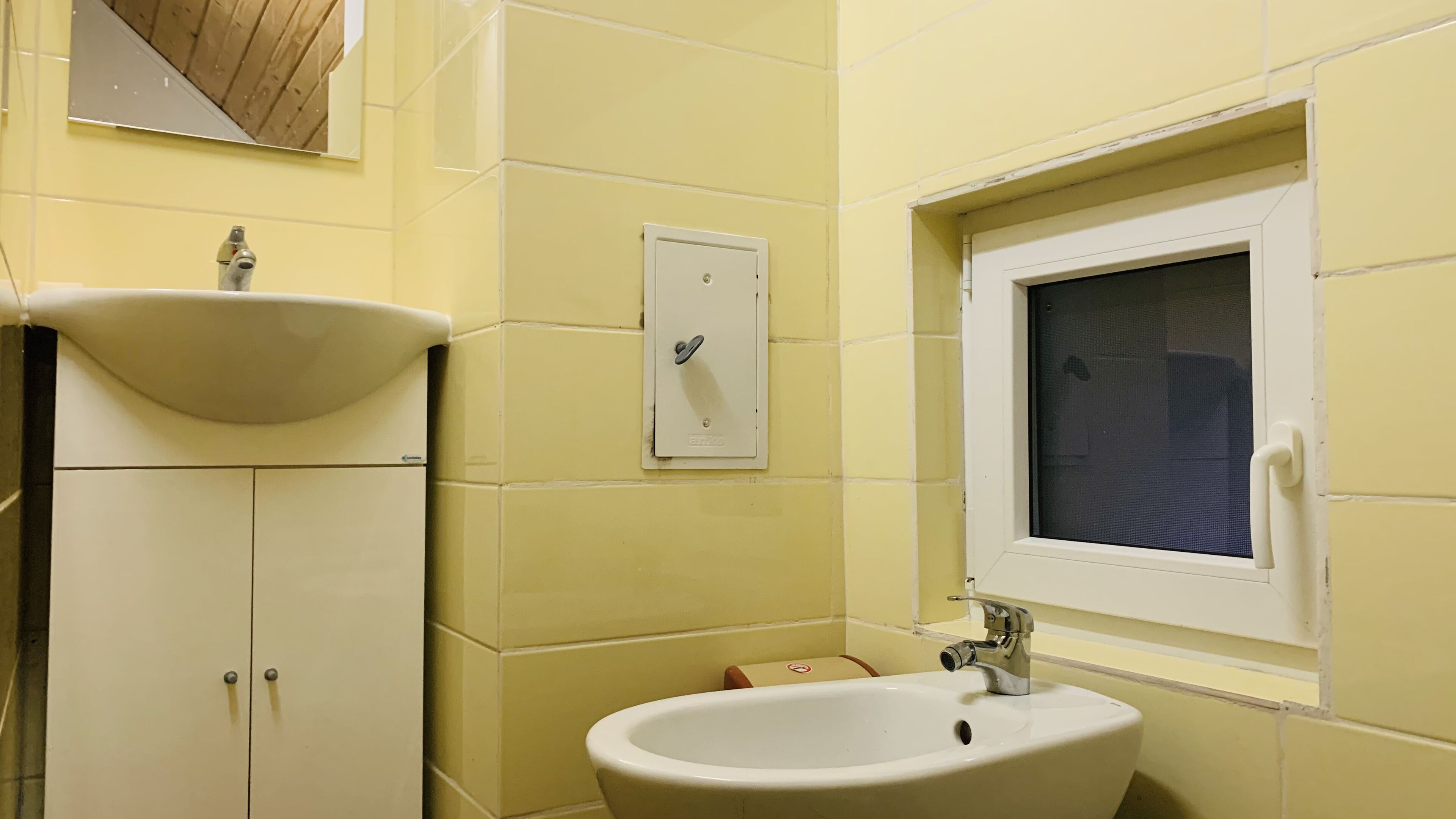 A bathroom with a sink, mirror, and window.