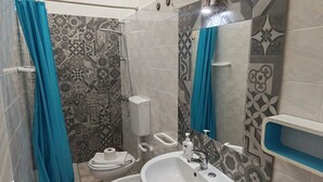 Un baño con ducha, inodoro, bidé y lavamanos.