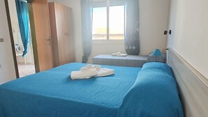 A room with a bed, a small table, a window with curtains, and a wardrobe. - Apartment with Veranda in Residence (TORRE SAN GIOVANNI)