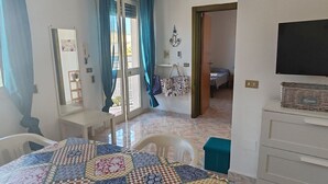 A hotel room with a checkered table, a bed, a TV, and a view of the outside. - Apartment with Veranda in Residence (TORRE SAN GIOVANNI)