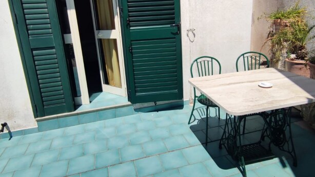 A patio with a table and chairs, a green door, and a potted plant. - La Palma Residence Two Bedroom Apartment (TORRE SAN GIOVANNI)