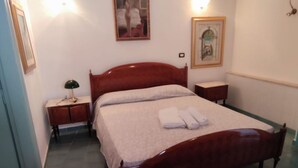 A neatly made bed with white linens and a folded towel, a bedside table with a lamp, and a framed picture on the wall. - RICHARD COMFORT - STUDIO APARTMENT WITH PATIO (TORRE SAN GIOVANNI)