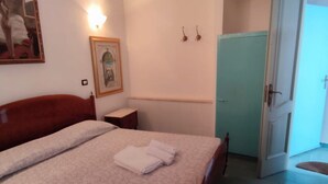 A bedroom with a bed, a nightstand, a framed picture, a light switch, and a door. - RICHARD COMFORT - STUDIO APARTMENT WITH PATIO (TORRE SAN GIOVANNI)