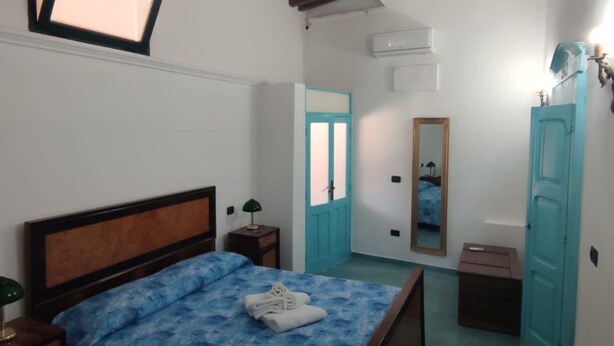 Une chambre à coucher avec un lit, une table de chevet, un miroir et une porte.