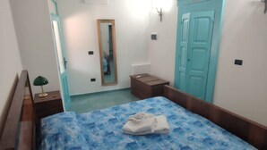 Une chambre à coucher comprenant un lit, une table de chevet, un miroir, une armoire et une porte.