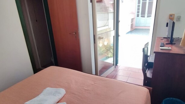 Une pièce avec un lit, un bureau avec un ordinateur et une fenêtre.