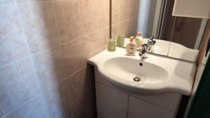Une salle de bain avec un lavabo blanc, un miroir et des murs carrelés.