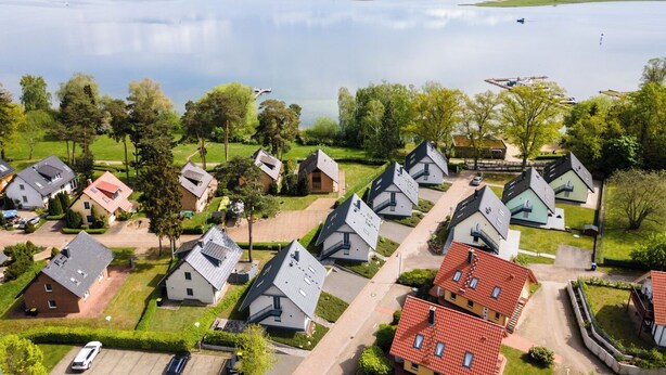 A residential area with houses, a lake, and a dock. - Strandhaus 2 OG in Röbel (Röbel/Müritz)