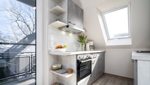 A modern kitchen with a built-in oven, a white countertop, and a window above the sink. - Strandhaus 2 OG in Röbel (Röbel/Müritz)