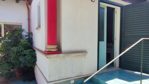 Un escalier doté d’une rampe métallique mène à une porte dont le cadre est bleu.