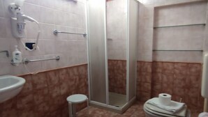 Une salle de bain équipée d’une douche, de toilettes, d’un lavabo et d’un petit tabouret.