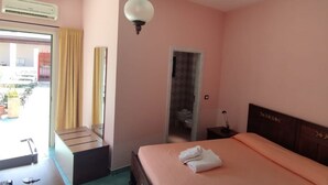 Une chambre à coucher comprenant un lit, une table de chevet, une lampe, une armoire, un miroir et un appareil de climatisation.