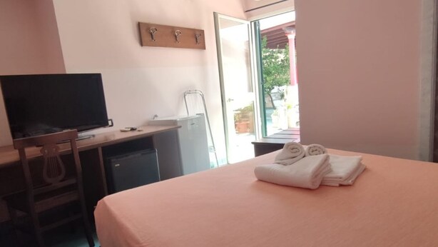 Une chambre à coucher avec un lit, un bureau avec un ordinateur, une chaise et une fenêtre donnant sur l’extérieur.