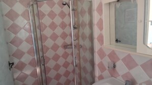 Une salle de bain avec une cabine de douche, un lavabo et un miroir.