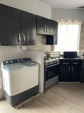 A kitchen with a gas stove, oven, and a microwave. There are cabinets above the stove and a countertop with a coffee maker. - Tropical Oasis in Managua (Nindiri)