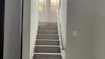 A staircase with wooden steps and a metal handrail, leading to a door with a window.