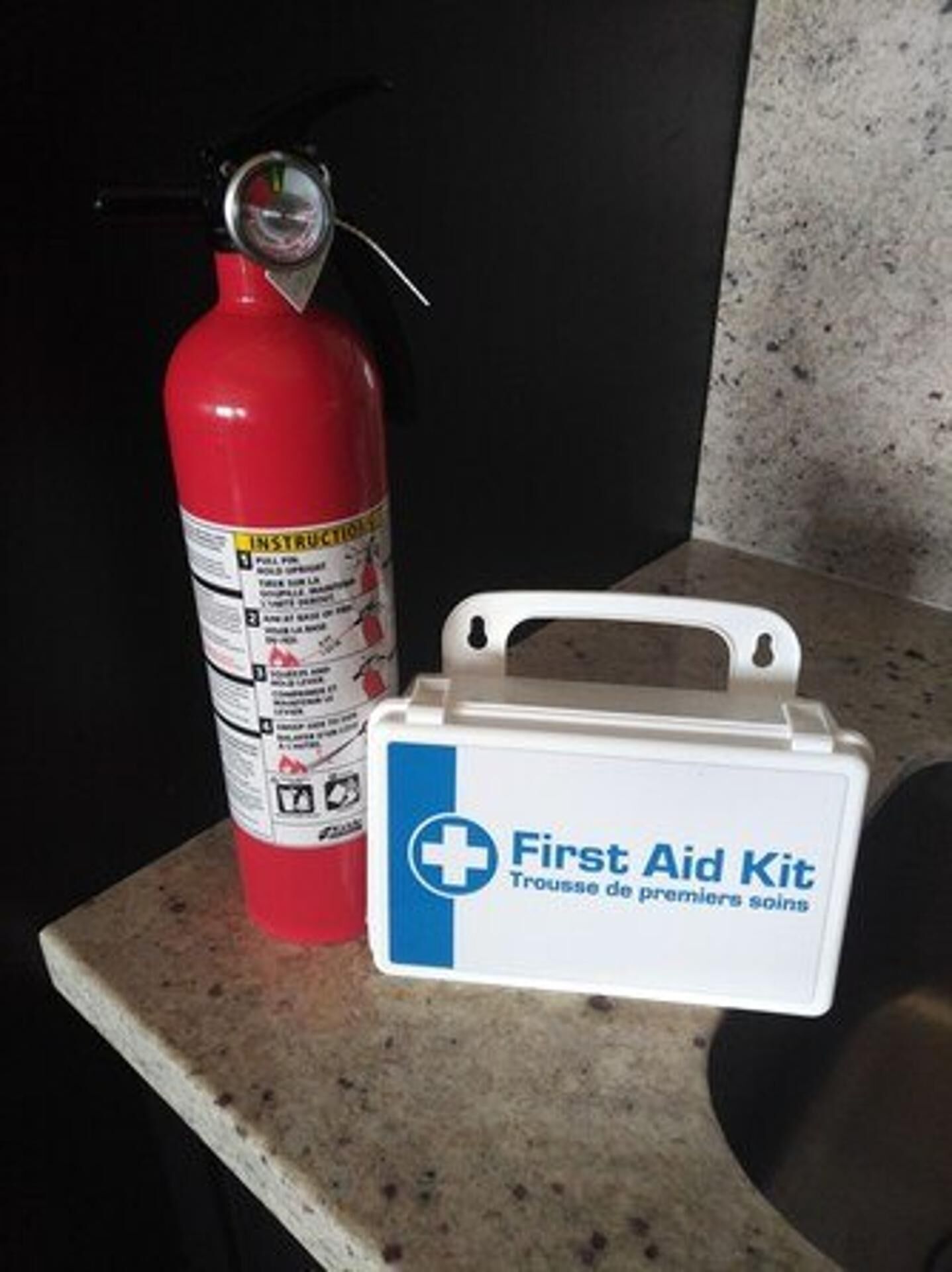 A red fire extinguisher and a white first aid kit on a countertop.