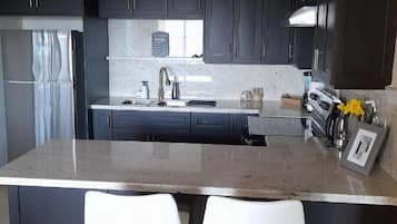 A kitchen with dark cabinets, a granite countertop, a stainless steel sink, and a coffee maker.