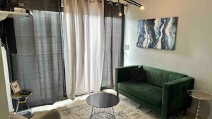 Un soggiorno moderno con un divano verde, un tavolino rotondo e un quadro appeso al muro.