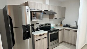 Una cucina moderna con elettrodomestici in acciaio inossidabile, forno a microonde integrato e mobili in legno chiaro.