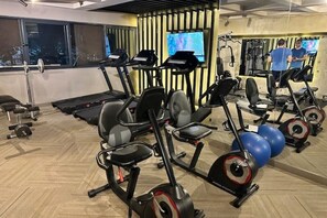 A gym with treadmills, elliptical machines, and exercise balls.