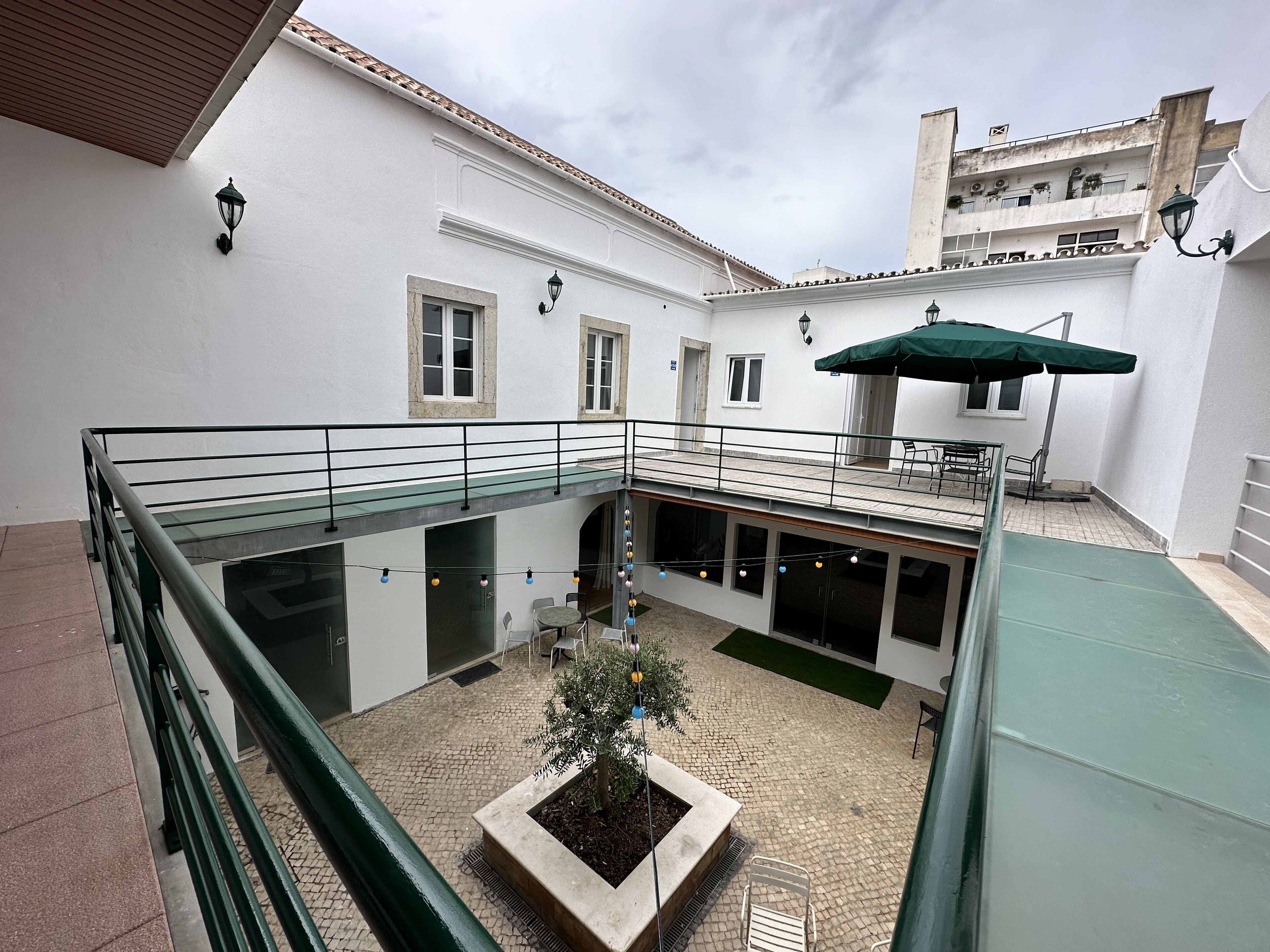 A courtyard with a glass balustrade, outdoor seating, and a potted plant.