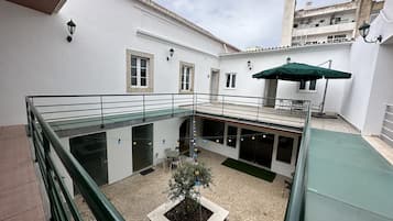 A courtyard with a glass balustrade, outdoor seating, and a potted plant.