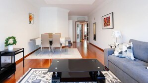 A modern living room with a sofa, a coffee table, and a dining area with chairs and a table. - LUXURY LISBOA APARTMENT T2 (Lisbon)